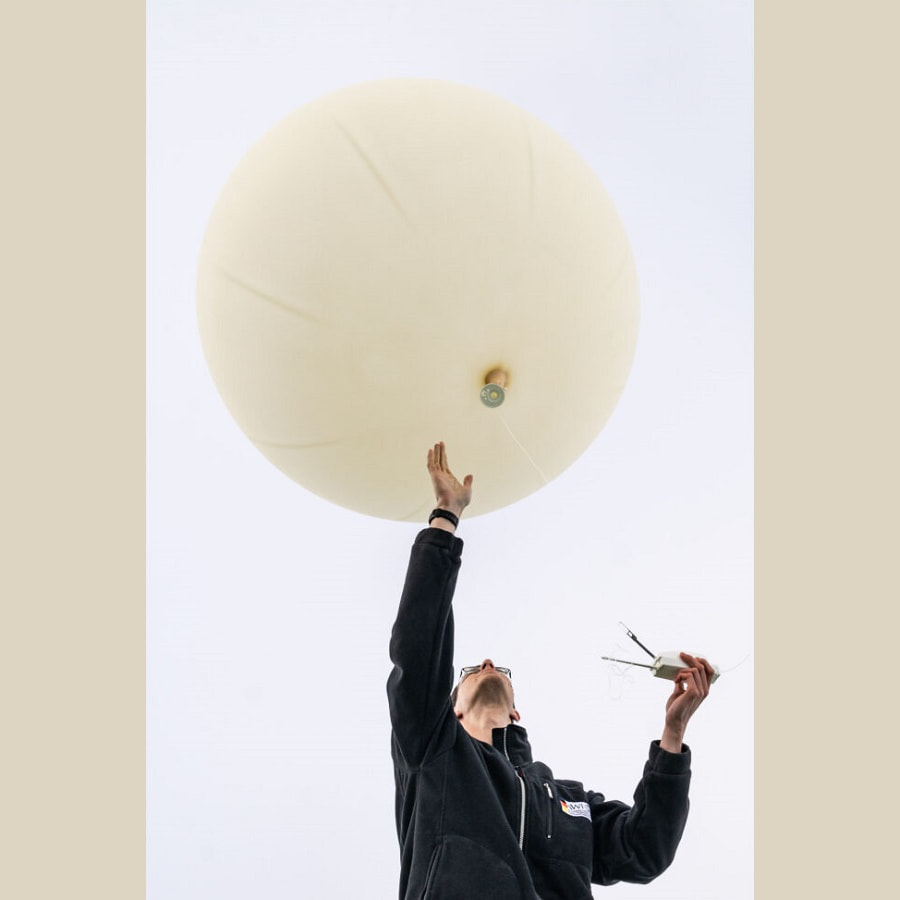 Andreas befestigt eine Radiosonde zum Messen an den Wetterballon, Foto: Christian Rohleder, Illustration: Simone Lindemann / Universität Leipzig